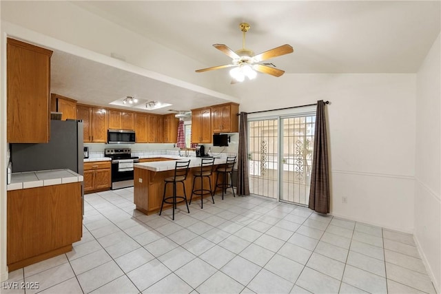 901 E Jaybird St, Pahrump, NV 89048 - kitchen featuring stainless steel appliances, a peninsula, lofted ceiling, a kitchen bar, and ceiling fan