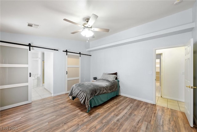 901 E Jaybird St, Pahrump, NV 89048 - bedroom featuring a barn door, wood finished floors, a ceiling fan, and ensuite bath