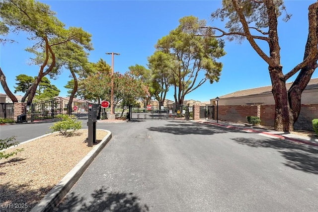 1717 Dwayne Stedman Ave, Las Vegas, NV 89106 - view of asphalt street featuring a gate, traffic signs, curbs, sidewalks, and a gated entry