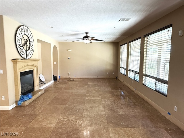 585 Via Alhambra, Las Vegas, NV 89123 - unfurnished living room featuring ceiling fan, arched walkways, a fireplace, and a textured ceiling