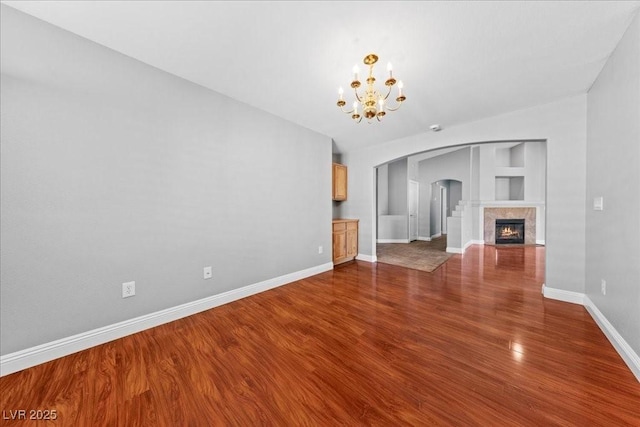 4029 Ricebird Way N, Las Vegas, NV 89084 - unfurnished living room featuring arched walkways, a chandelier, built in shelves, dark wood-type flooring, and a fireplace