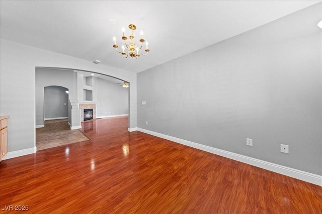 4029 Ricebird Way N, Las Vegas, NV 89084 - unfurnished living room featuring arched walkways, a chandelier, wood finished floors, and a fireplace