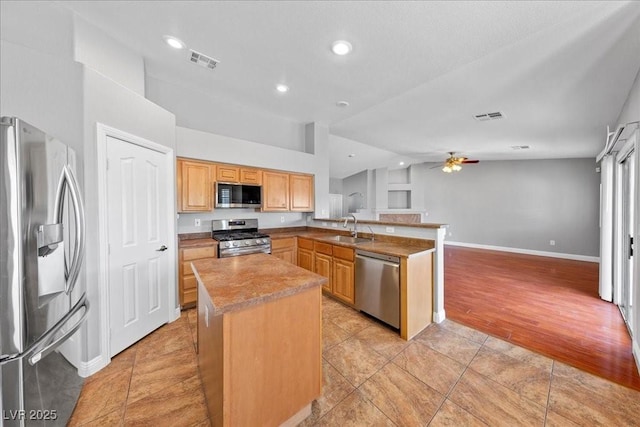 4029 Ricebird Way N, Las Vegas, NV 89084 - kitchen featuring stainless steel appliances, a peninsula, a ceiling fan, a kitchen island, and vaulted ceiling