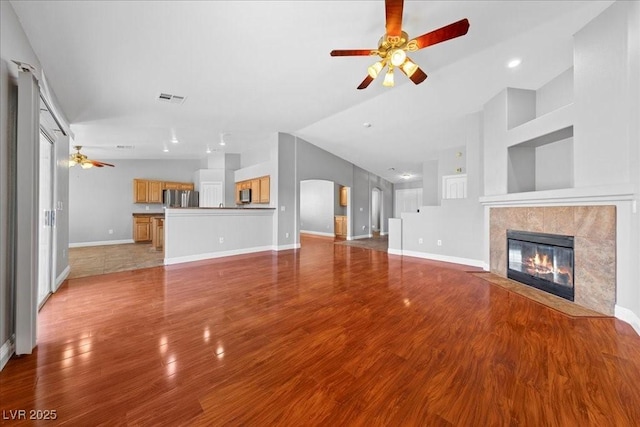 4029 Ricebird Way N, Las Vegas, NV 89084 - unfurnished living room with a ceiling fan, a tiled fireplace, wood finished floors, arched walkways, and recessed lighting