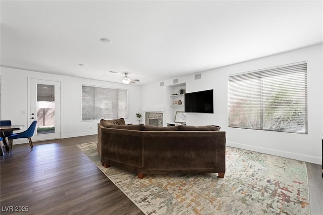 2229 Armacost Dr, Henderson, NV 89074 - living room with wood finished floors, a ceiling fan, built in shelves, and a fireplace