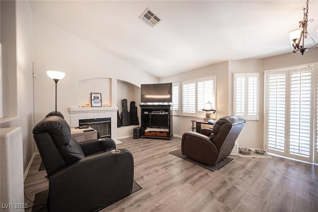 7231 Sequoia Springs Dr, Las Vegas, NV 89147 - living area with wood finished floors, a tiled fireplace, lofted ceiling, and a chandelier