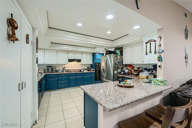 6616 Celeste Ave, Las Vegas, NV 89107 - kitchen with blue cabinets, a raised ceiling, black appliances, a peninsula, and white cabinets