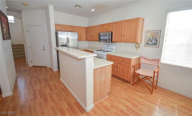 6098 Darkfeather Way, Las Vegas, NV 89139 - kitchen with stainless steel appliances, light wood-style flooring, light countertops, a kitchen island, and arched walkways