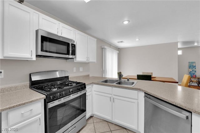 9957 Fine Fern St, Las Vegas, NV 89183 - kitchen featuring appliances with stainless steel finishes, a peninsula, white cabinetry, recessed lighting, and light tile patterned floors