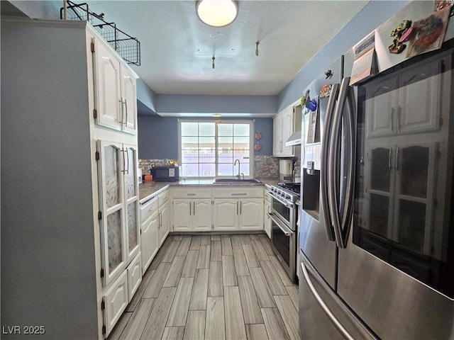 4823 El Tesoro Ave, Las Vegas, NV 89121 - kitchen with stainless steel appliances, white cabinets, decorative backsplash, wood tiled floors, and under cabinet range hood