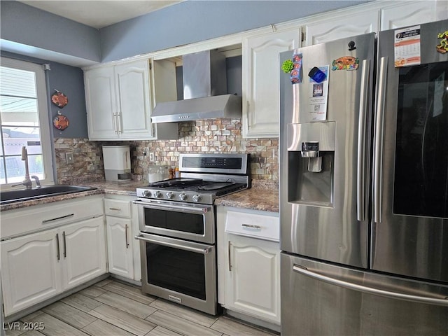 4823 El Tesoro Ave, Las Vegas, NV 89121 - kitchen with appliances with stainless steel finishes, wall chimney range hood, white cabinetry, and tasteful backsplash