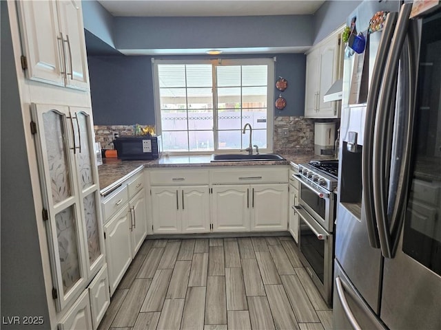 4823 El Tesoro Ave, Las Vegas, NV 89121 - kitchen with stainless steel appliances, white cabinets, decorative backsplash, wood tiled floors, and custom exhaust hood