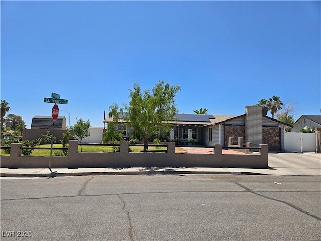 4823 El Tesoro Ave, Las Vegas, NV 89121 - view of front facade with a fenced front yard, solar panels, driveway, and a gate