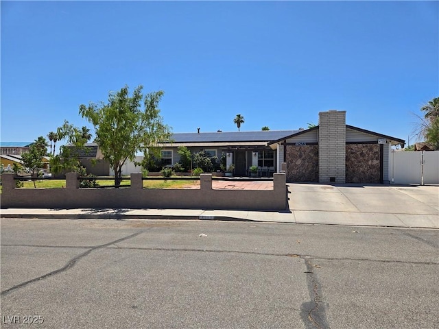 4823 El Tesoro Ave, Las Vegas, NV 89121 - view of front of home with a fenced front yard, concrete driveway, roof mounted solar panels, an attached garage, and a chimney