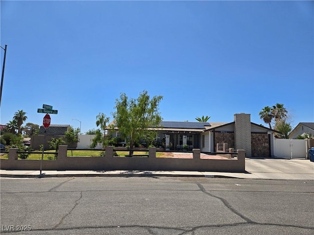 4823 El Tesoro Ave, Las Vegas, NV 89121 - view of front of house featuring a fenced front yard, solar panels, driveway, and a gate