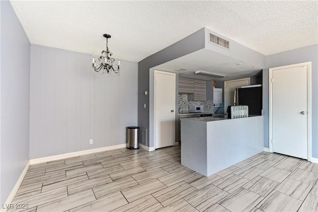 1372 Lorilyn Ave Unit 3, Las Vegas, NV 89119 - kitchen featuring a peninsula, white microwave, a textured ceiling, wood tiled floors, and a chandelier