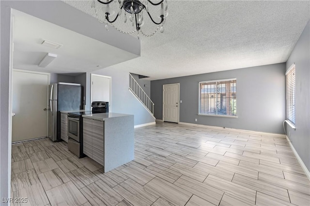 1372 Lorilyn Ave Unit 3, Las Vegas, NV 89119 - kitchen featuring stainless steel range with electric stovetop, a chandelier, a textured ceiling, a peninsula, and open floor plan