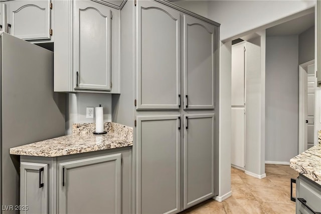 3337 Partridge Run St, Laughlin, NV 89029 - kitchen featuring gray cabinetry, freestanding refrigerator, and light stone countertops