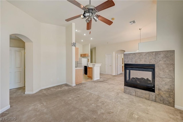 8768 Tom Noon Ave Unit 101, Las Vegas, NV 89178 - unfurnished living room with arched walkways, light colored carpet, a ceiling fan, a fireplace, and high vaulted ceiling