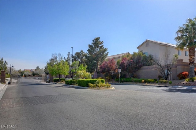 8768 Tom Noon Ave Unit 101, Las Vegas, NV 89178 - view of asphalt road with curbs, a gate, street lighting, and a gated entry