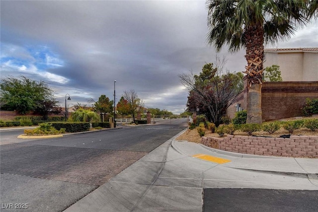 8768 Tom Noon Ave Unit 101, Las Vegas, NV 89178 - view of asphalt road with curbs, a gated entry, and street lights