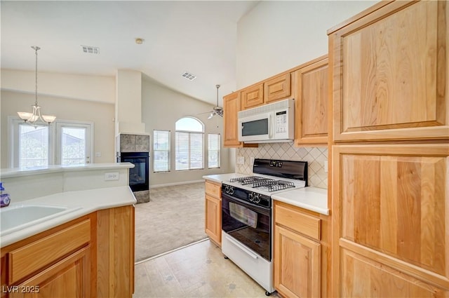 8768 Tom Noon Ave Unit 101, Las Vegas, NV 89178 - kitchen featuring white microwave, gas range, vaulted ceiling, ceiling fan, and a tile fireplace