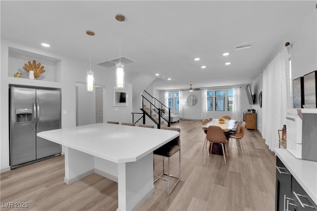 8072 Haywood Estate Ave, Las Vegas, NV 89113 - kitchen with stainless steel refrigerator with ice dispenser, light countertops, a breakfast bar area, a kitchen island, and recessed lighting