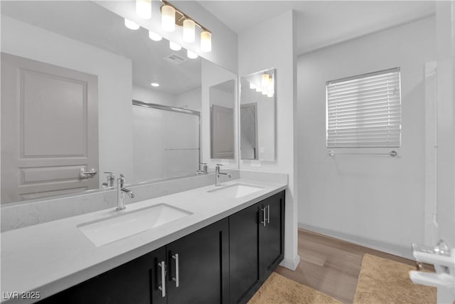 8072 Haywood Estate Ave, Las Vegas, NV 89113 - bathroom featuring double vanity, a shower with door, and wood finished floors