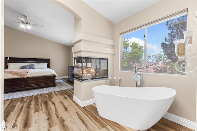 5452 Desert Spring Rd, Las Vegas, NV 89149 - bedroom featuring lofted ceiling, wood finished floors, and a multi sided fireplace