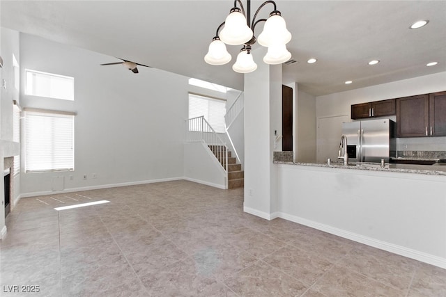 1663 Cloister Ave, Henderson, NV 89014 - kitchen with stainless steel refrigerator with ice dispenser, dark brown cabinets, recessed lighting, a chandelier, and light stone counters