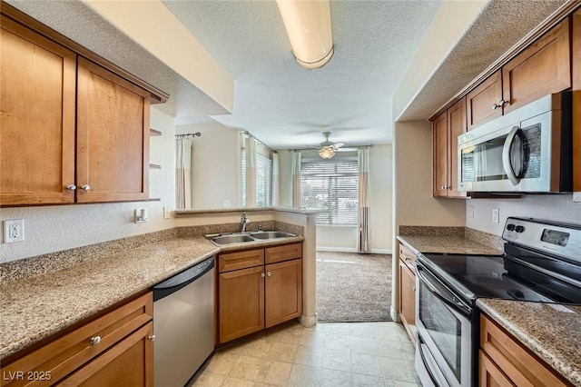 4400 S Jones Blvd Unit 2007, Las Vegas, NV 89103 - kitchen with stainless steel appliances, a peninsula, brown cabinets, a ceiling fan, and a textured ceiling