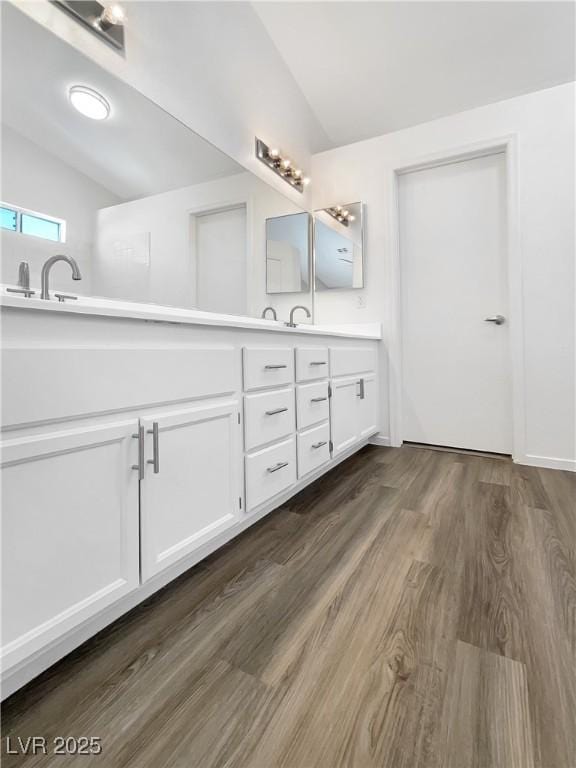 6696 Merced Lake Dr, Las Vegas, NV 89156 - bathroom featuring double vanity, vaulted ceiling, and wood finished floors