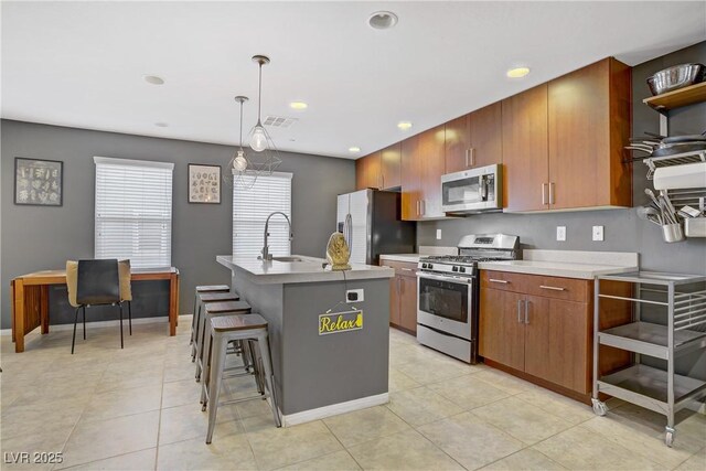 9050 W Tropicana Ave Unit 1027, Las Vegas, NV 89147 - kitchen with stainless steel appliances, a center island with sink, open shelves, light countertops, and decorative light fixtures