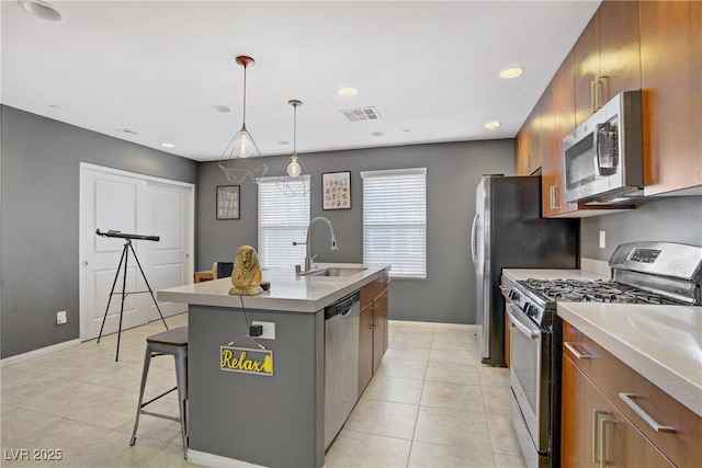 9050 W Tropicana Ave Unit 1027, Las Vegas, NV 89147 - kitchen with stainless steel appliances, brown cabinetry, a kitchen island with sink, light tile patterned floors, and recessed lighting