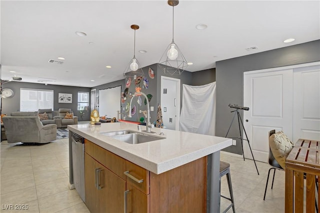 9050 W Tropicana Ave Unit 1027, Las Vegas, NV 89147 - kitchen featuring a kitchen island with sink, brown cabinets, light tile patterned floors, open floor plan, and hanging light fixtures