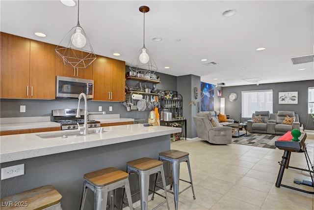 9050 W Tropicana Ave Unit 1027, Las Vegas, NV 89147 - kitchen featuring stainless steel appliances, brown cabinetry, a kitchen bar, recessed lighting, and light tile patterned flooring
