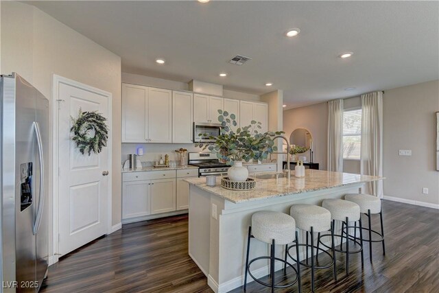 7705 Alder Forest St, Las Vegas, NV 89113 - kitchen featuring stainless steel appliances, dark wood-style flooring, white cabinetry, a center island with sink, and recessed lighting