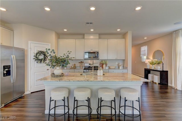 7705 Alder Forest St, Las Vegas, NV 89113 - kitchen featuring stainless steel appliances, a breakfast bar area, light stone counters, dark wood finished floors, and recessed lighting