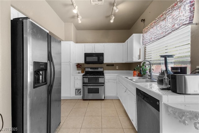 2500 Cortina Ave, Henderson, NV 89074 - kitchen featuring stainless steel appliances, tile countertops, track lighting, white cabinets, and light tile patterned floors