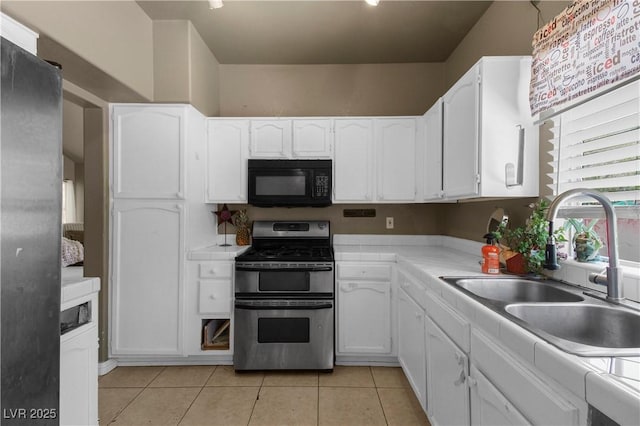 2500 Cortina Ave, Henderson, NV 89074 - kitchen with black microwave, double oven range, white cabinets, tile counters, and light tile patterned flooring