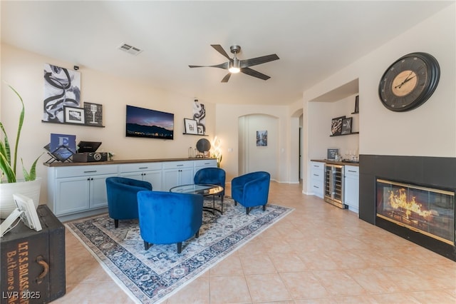 8605 Trianon Ln, Las Vegas, NV 89145 - living area featuring wine cooler, a ceiling fan, arched walkways, a bar, and light tile patterned flooring
