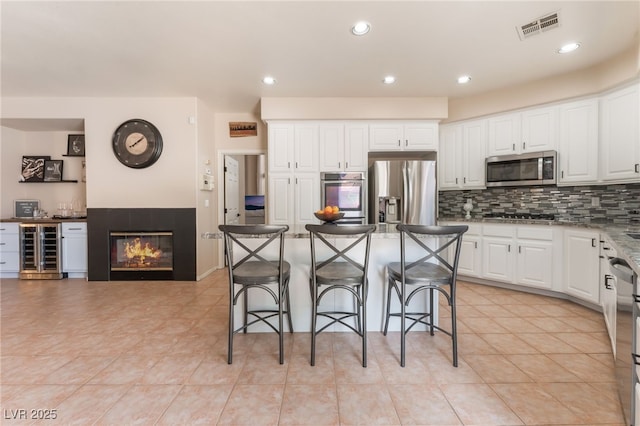 8605 Trianon Ln, Las Vegas, NV 89145 - kitchen featuring stainless steel appliances, beverage cooler, tasteful backsplash, a kitchen bar, and white cabinets