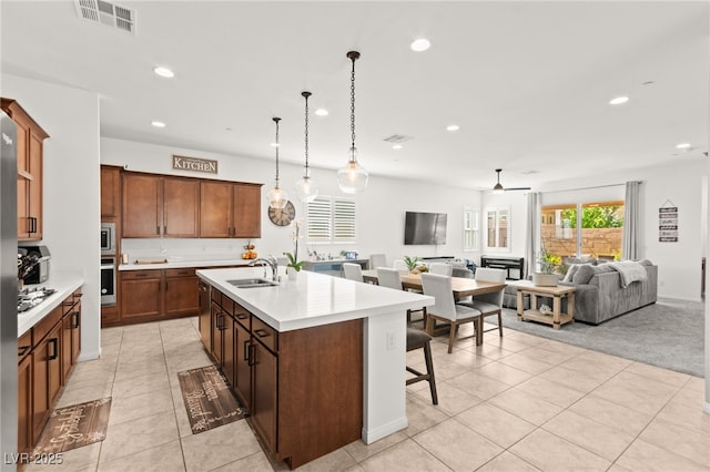10160 Tree Blossom Ave, Las Vegas, NV 89166 - kitchen with light countertops, recessed lighting, a breakfast bar, stainless steel appliances, and an island with sink