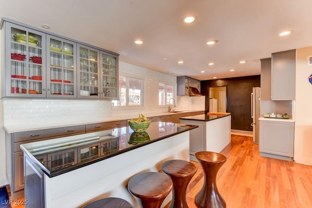 1818 Waldman Ave, Las Vegas, NV 89102 - kitchen with a kitchen island, light wood-type flooring, recessed lighting, decorative backsplash, and glass insert cabinets