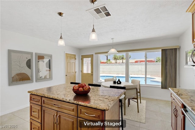 6358 Meadow Lark Ln, Las Vegas, NV 89103 - kitchen with pendant lighting, light tile patterned flooring, brown cabinets, a center island, and light stone counters