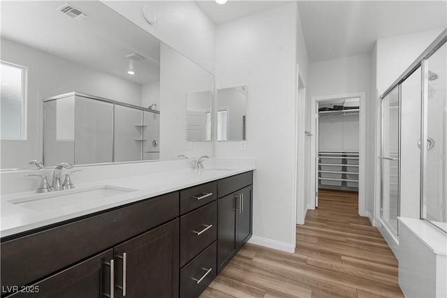 5936 Bruselas St, Las Vegas, NV 89113 - bathroom with a stall shower, a spacious closet, double vanity, and wood finished floors