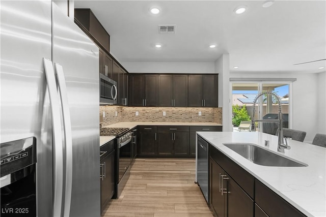 5936 Bruselas St, Las Vegas, NV 89113 - kitchen with stainless steel appliances, light wood finished floors, backsplash, recessed lighting, and light stone counters