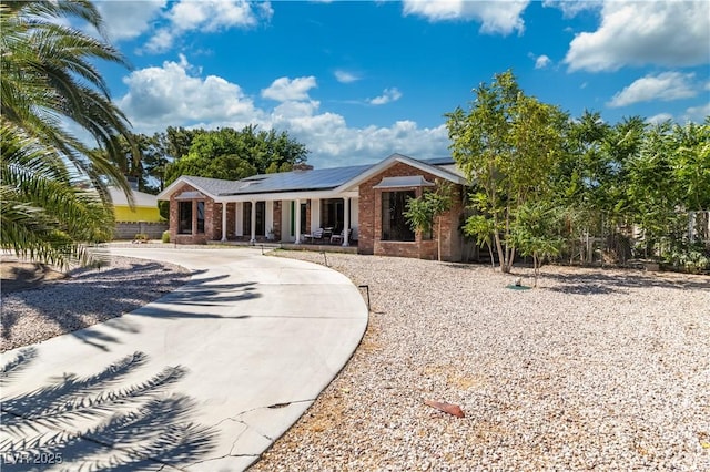 5486 Alfred Dr, Las Vegas, NV 89108 - single story home with covered porch, brick siding, roof mounted solar panels, and curved driveway