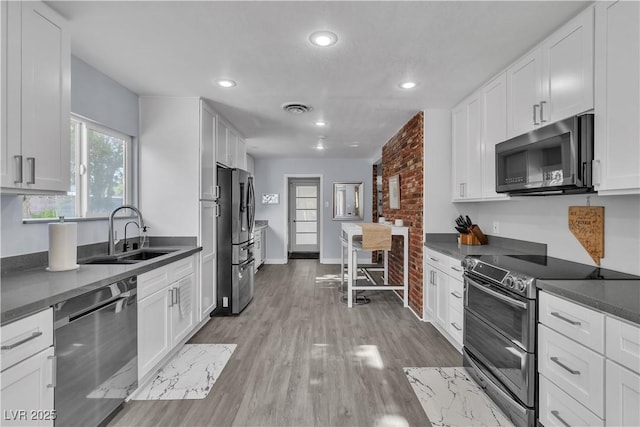 5486 Alfred Dr, Las Vegas, NV 89108 - kitchen with appliances with stainless steel finishes, dark countertops, white cabinets, and recessed lighting