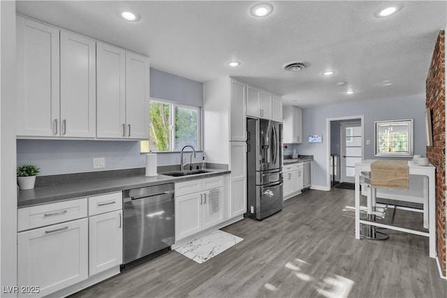 5486 Alfred Dr, Las Vegas, NV 89108 - kitchen featuring appliances with stainless steel finishes, white cabinets, recessed lighting, wood finished floors, and dark countertops
